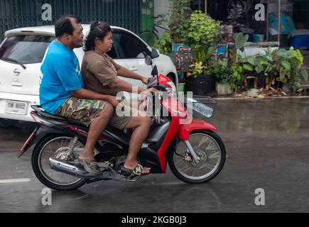 Ratchaburi, Thailand, NOVEMBER 14 2022, Ein Paar fährt Motorrad auf einer nassen Straße Stockfoto