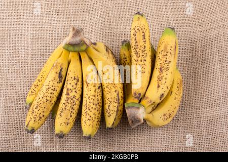 Ein Haufen gelber Sommersprossen-Bananen auf einer Leinwandstruktur Stockfoto
