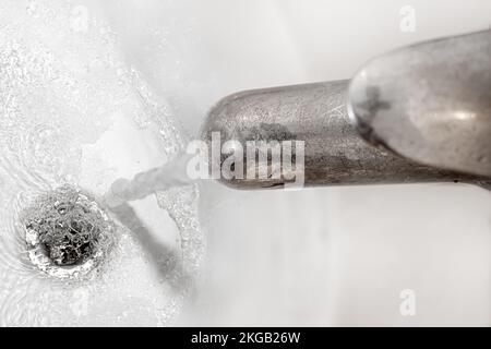 Wasser fließt aus dem Wasserhahn über der Ablauföffnung in der Wanne Stockfoto