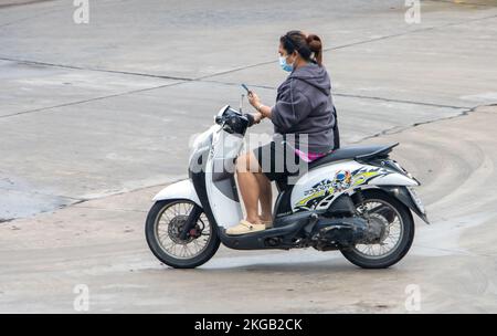 SAMUT PRAKAN, THAILAND, 26 2022. September, Eine Frau mit Handy in der Hand fährt ein Motorrad Stockfoto