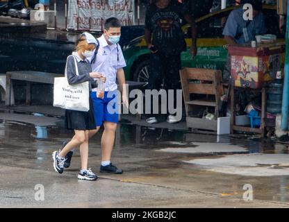 SAMUT PRAKAN, THAILAND, SEP 23 2022, Ein Junge und ein Mädchen in Schuluniformen gehen auf einer nassen Straße Stockfoto