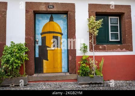 Farbenfroh bemalte Tür mit Turm des Forte de Sao Tiago und Pflanzen an der Fassade des Hauses, Kunstprojekt Arte de Portas abertas, Rua de Santa Maria, Ol Stockfoto