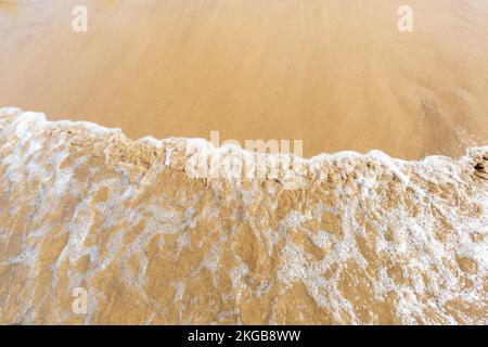 Ozean Strand von oben mit blauem Wasser, Wellen mit Schaum und Spray und feinem Sand, wunderschöne Sommerurlaube Stockfoto