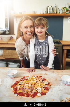 Kochen ist Liebe, die essbar ist. Eine Familie, die zu Hause Pizza genießt. Stockfoto