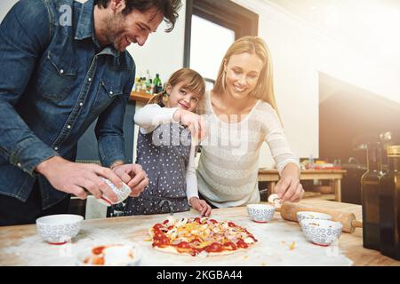 Genießen Sie das Leben, es ist köstlich. Eine Familie, die zu Hause Pizza genießt. Stockfoto