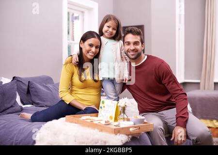 Die Routine zum Muttertag. Ein Mann und seine Tochter bringen seiner Frau am Muttertag Frühstück ins Bett. Stockfoto