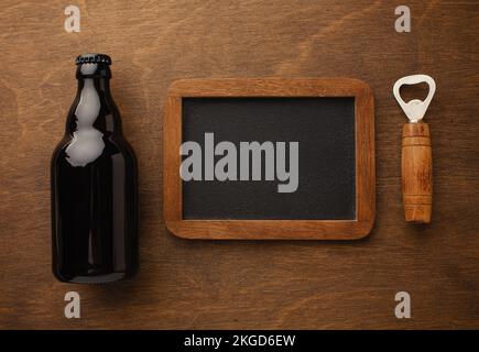 Eine Flasche Bier auf einem Teller mit gesalzenen Auberginen Brezeln, Pistaziennüssen und Chips auf einem schwarzen, zerkratzten Kreidetafel. Draufsicht. Hochwertiges Foto Stockfoto