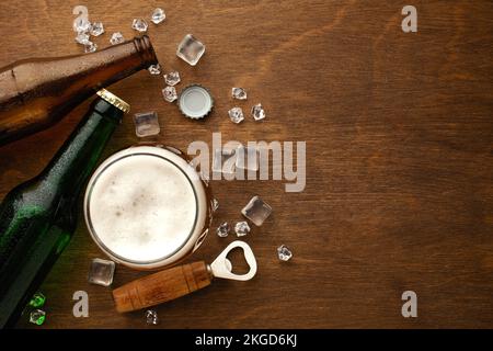 Eine Flasche Bier auf einem Teller mit gesalzenen Auberginen Brezeln, Pistaziennüssen und Chips auf einem schwarzen, zerkratzten Kreidetafel. Draufsicht. Hochwertiges Foto Stockfoto