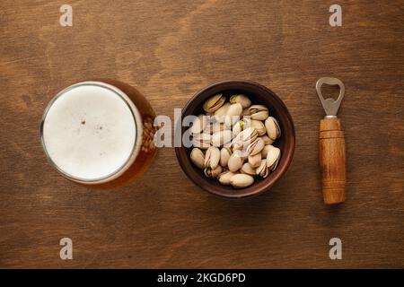 Eine Flasche Bier auf einem Teller mit gesalzenen Auberginen Brezeln, Pistaziennüssen und Chips auf einem schwarzen, zerkratzten Kreidetafel. Draufsicht. Hochwertiges Foto Stockfoto