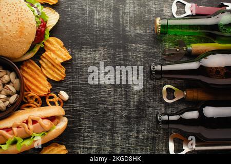 Eine Flasche Bier und verschiedene Snacks auf einem rustikalen Holztisch. Draufsicht. Hochwertiges Foto Stockfoto