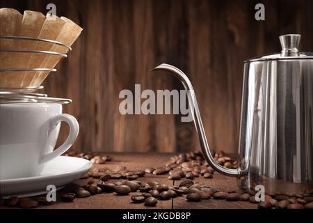 Alternative Kaffeezubereitung. Gießen Sie Über Tropf-Kaffeemaschine Wasserkocher Mit Schwanenhals. Kaffeepapierfilter Im Kabelhalter Auf Weißem Keramikbecher. Stockfoto