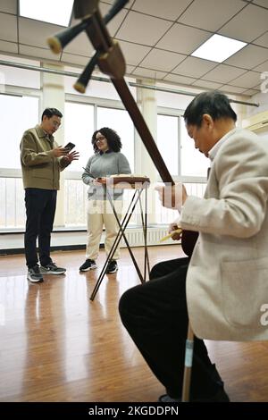 (221123) -- TIANJIN, 23. November 2022 (Xinhua) -- Amiris Rodrigues Barros (C) erlernt den „Jingdong Dagu“ von ihrem Meister Wang Wenlei (L) in einem Klassenzimmer der Nankai-Universität in Nordchina Tianjin, 20. November 2022. Amiris Rodrigues Barros, ein brasilianisches Mädchen, das für einen Master-Abschluss an der Nankai University in Nordchina Tianjin arbeitet, hat eine faszinierende Liebe zur traditionellen chinesischen Kultur. Zum ersten Mal hing sie an China, als sie noch auf der Highschool in ihrer Heimat war, wo sie chinesische Kurse besuchte und besonderes Interesse an chinesischer Küche und interessanten Orten wuchs. Bis später, sh Stockfoto