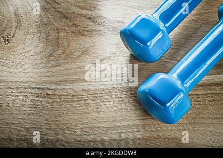 Blaue Kurzhantel-Gewichte auf Holzbrett-Fitnesskonzept. Stockfoto
