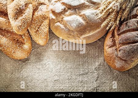 Braunbrotbrot-Brotstift-Weizenohren auf hessischem Hintergrund. Stockfoto