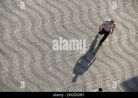 Leute, die an sonnigen Tagen mit Schatten auf der Straße laufen, auf dem Foto von der Spitze des Gebäudes. (Surabaya, Indonesien - 27. Oktober 2018) Stockfoto