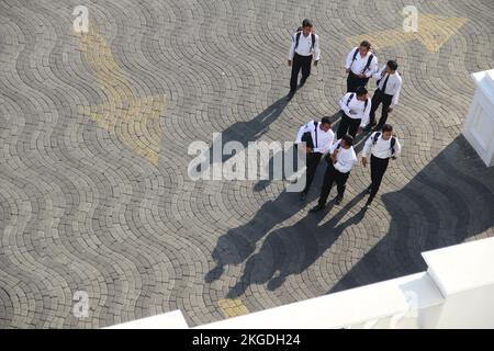 Leute, die an sonnigen Tagen mit Schatten auf der Straße laufen, auf dem Foto von der Spitze des Gebäudes. (Surabaya, Indonesien - 27. Oktober 2018) Stockfoto