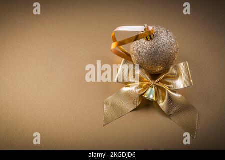 Weihnachtskugel mit Schleife auf goldenem Hintergrund. Stockfoto