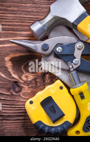 Klauenhammer-Konstruktionshandschuh Bandschraubendreher und Zange auf altem Holzbrett Stockfoto