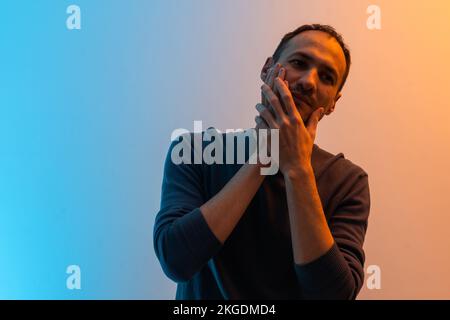 Zahnschmerzen. Junger Mann, der Schmerzen spürt, seine Wange mit beiden Händen hält, an Zahnschmerzen leidet, schmerzhafte Ausdrucksweise hat. Stockfoto