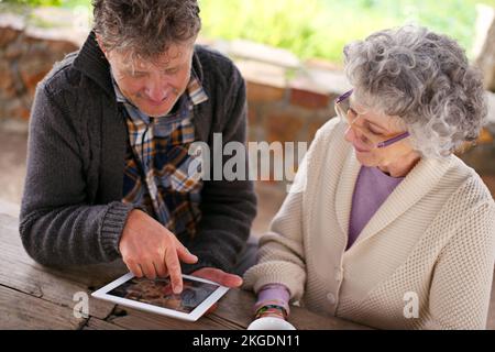 Nie zu alt, um Neues zu lernen. Aufnahmen eines Seniorenpaares mit einem digitalen Tablet aus einem hohen Winkel. Stockfoto