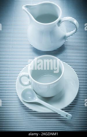 Kaffeetasse Untertasse Teelöffel Creme auf gestreiftem Hintergrund. Stockfoto