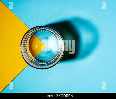 Brille mit Wasser auf zweifarbiges Hintergrundbild, Draufsicht Stockfoto