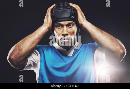 Konzentration vor dem Spiel. Studioaufnahme eines entschlossenen jungen Rugbyspielers. Stockfoto