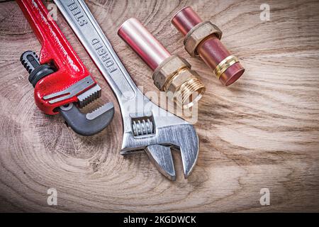 Kupferwasserrohrzange Nippel Schlauchanschlüsse verstellbarer Schlüssel auf Holztafelrohrleitungen Konzept. Stockfoto