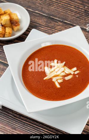 Tomatensuppe mit Käse in weißer Porzellanschüssel Stockfoto