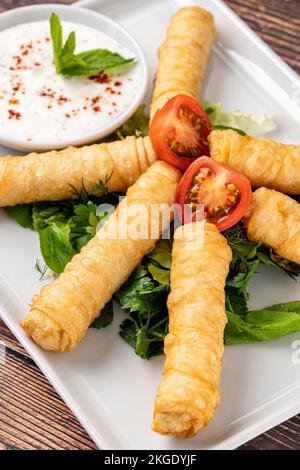 Türkische Zigarrenrollen auf einer weißen Porzellanplatte. Der türkische Name ist Sigara Boregi Stockfoto