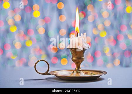 Handschuhkerze in altem Kerzenhalter auf Bokeh-Hintergrund Stockfoto