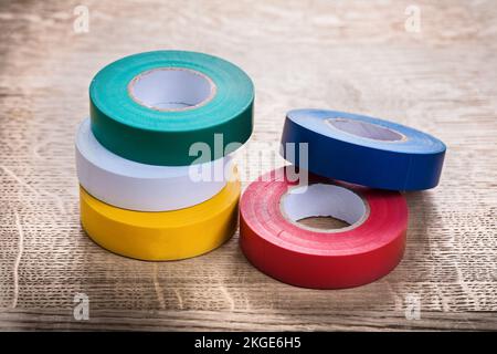 Grünweiß gelblich rot-blaue Rollen Isolierband auf Holzplatten Baukonzept Stockfoto