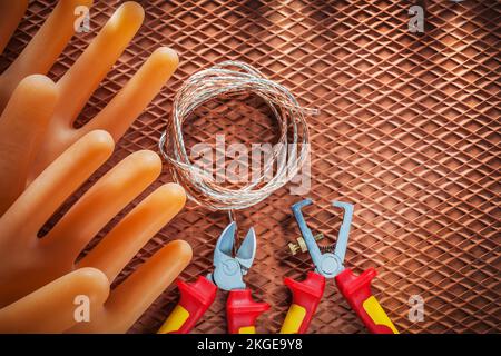 Abisolierzangen Schneiden von elektrischen Drähten Sicherheits-Isolierhandschuhe auf dielektrischer Abdeckung. Stockfoto