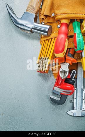 Werkzeuge für den Werkzeugbandbau aus Leder auf Betonhintergrund. Stockfoto