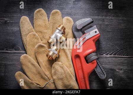 Monkey-Schraubenschlüssel Sanitärarmaturen Lederschutzhandschuhe auf Holzbrett. Stockfoto