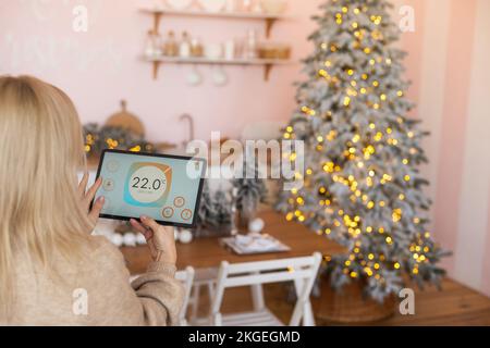 Junge Frau verwendet Anwendung in seinem Smart Home zu Weihnachten Stockfoto