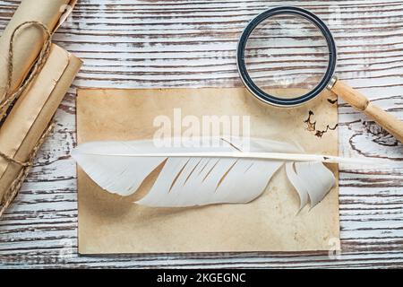 Alte Blattpapierrolle mit Federlupe auf altem Holzbrett. Stockfoto