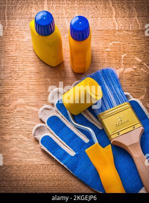 Malerwalzenflaschenbürste mit Sicherheitshandschuhen auf Holzbrett Stockfoto