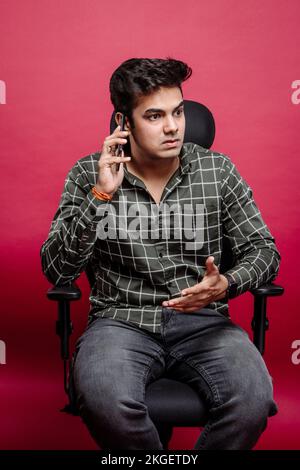 Gestresster und frustrierter, streitender Boss über das Handy im Studio-Hintergrund. Wütende Männer, die auf ihrem Smartphone diskutieren oder Probleme lösen. Stockfoto