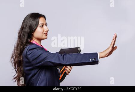 Nahaufnahme einer jungen Frau, die eine Stoppbewegung mit der Hand macht. Isoliertes Porträt eines jungen indischen weiblichen Modells mit Stoppschild. Halten Sie die Haltung an. Stockfoto