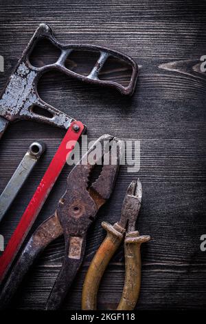 Rostige Handsäge-Drahtschneider-Zange im Vintage-Design auf Holzplatten. Stockfoto