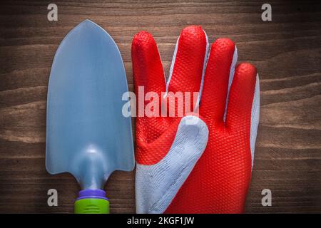Schutzhandschuh und Handspaten für Edelgärtnereien auf Holzbrettern. Stockfoto