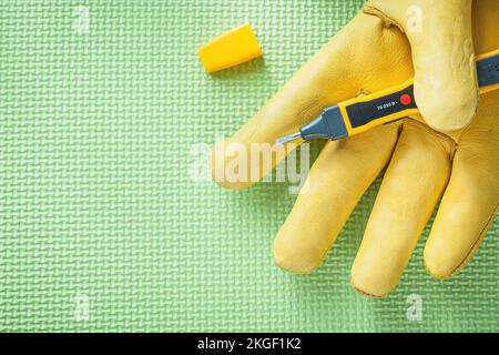 Sicherheitshandschuh Elektrotester auf grünem Hintergrund Stromkonzept. Stockfoto