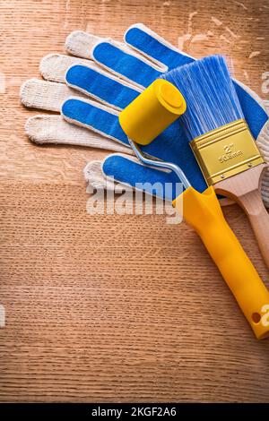 Schutzhandschuhe mit Malerwalze und Pinsel auf Holzbrettern Baukonzept Stockfoto