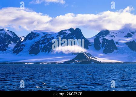 Felsige Küste in Svalbard mit schneebedeckten Bergen Stockfoto