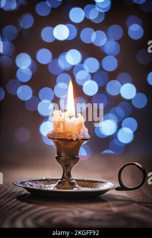 Klassischer Kerzenhalter mit Kerze auf verschwommenem Hintergrund. Stockfoto