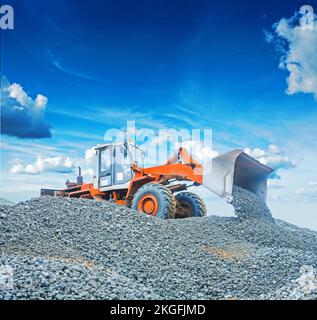 Radladerbagger, der mit Kies auf großen Haufen arbeitet Stockfoto