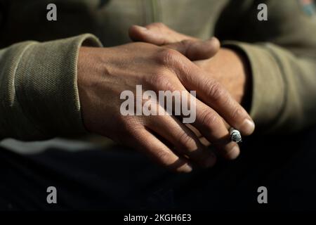 Hand in Detail. Zigarette zwischen Packungen. Licht auf der Rückseite der Bürste. Stockfoto