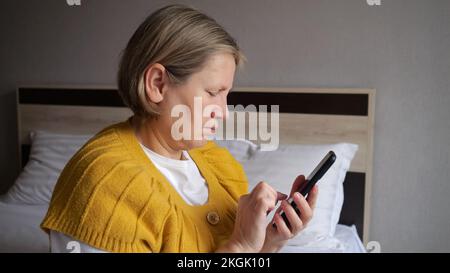 Eine einsame, reife Frau verträgt Depressionen beim Schreiben von Nachrichten Stockfoto