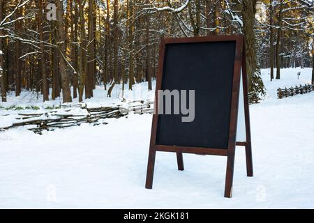 Nahaufnahme des Kreidetafelmenüs draußen auf dem Schnee. Winter-Menü-Anzeige in den Bergen. Stockfoto